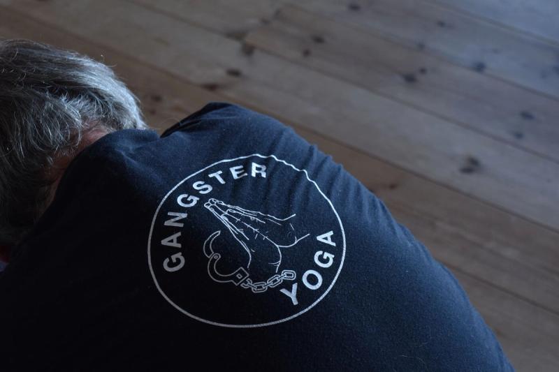 Gangster Yoga-logoen på ryggen av en svart T-skjorte