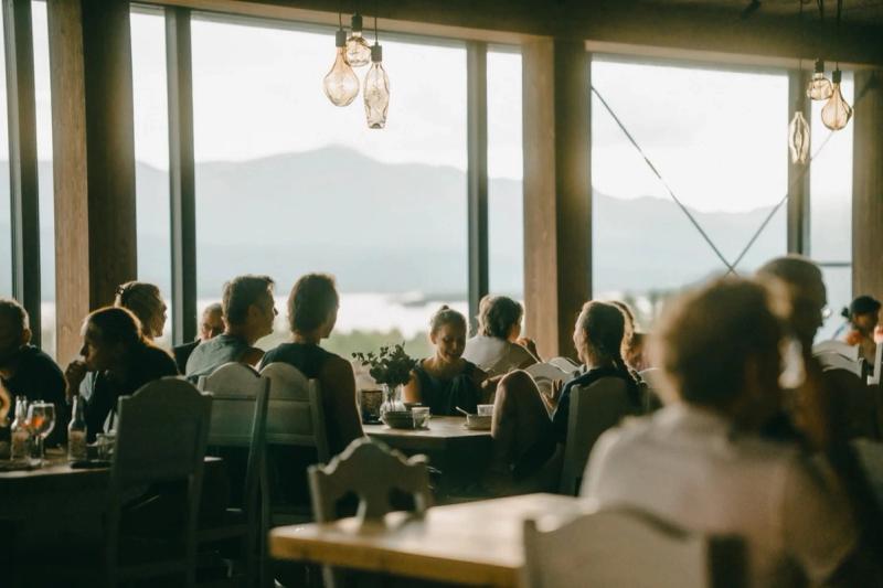 Gjester til middag ved store vinduer med utsikt mot fjellene