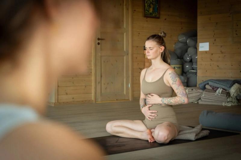 A woman meditating cross-legged in the shala