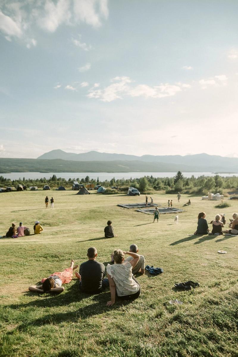 Guests sitting on the lawn above the lake in summer