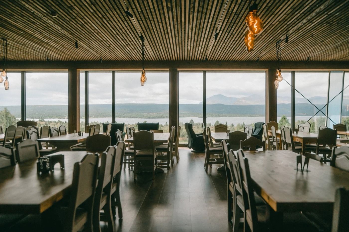 Spisesalen med trebord og vid utsikt over vannet og fjellene