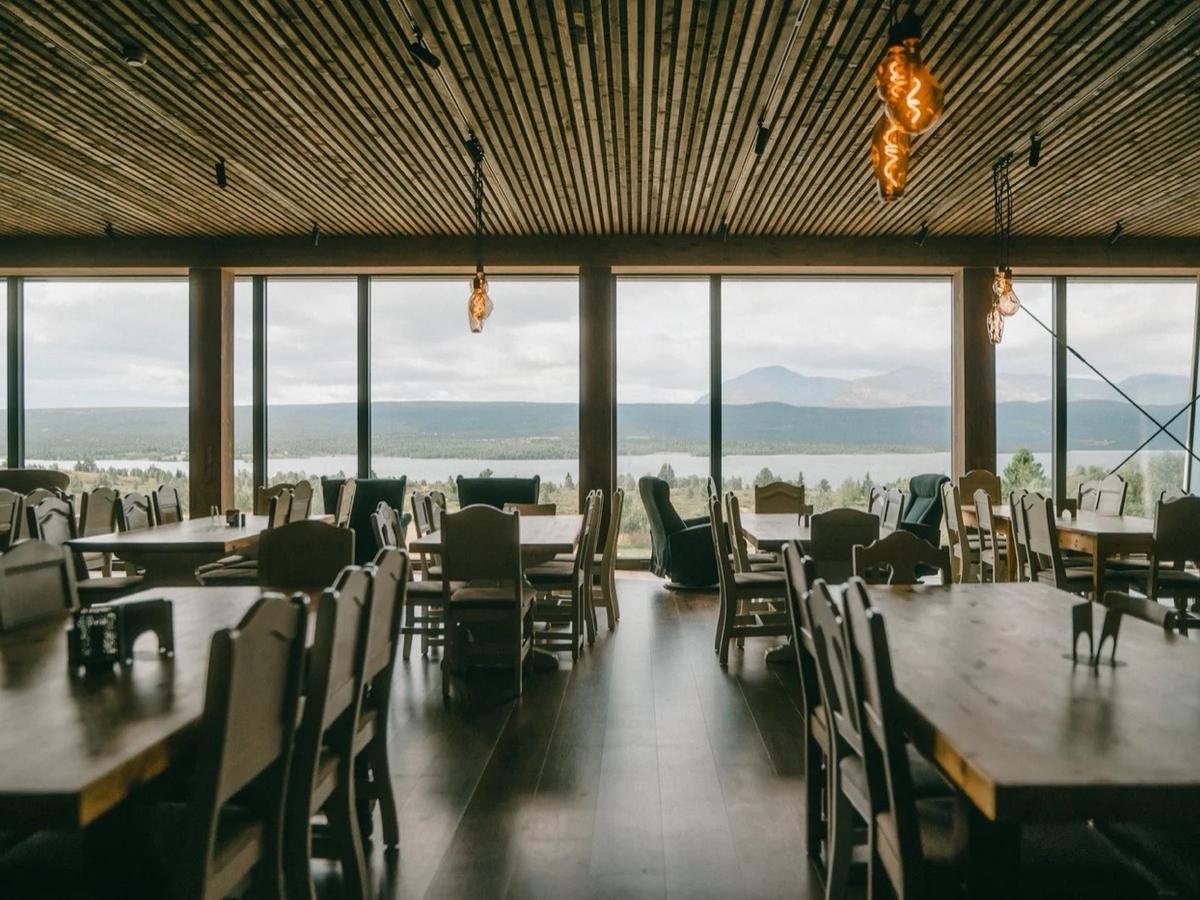 Spisesalen med trebord og vid utsikt over vannet og fjellene