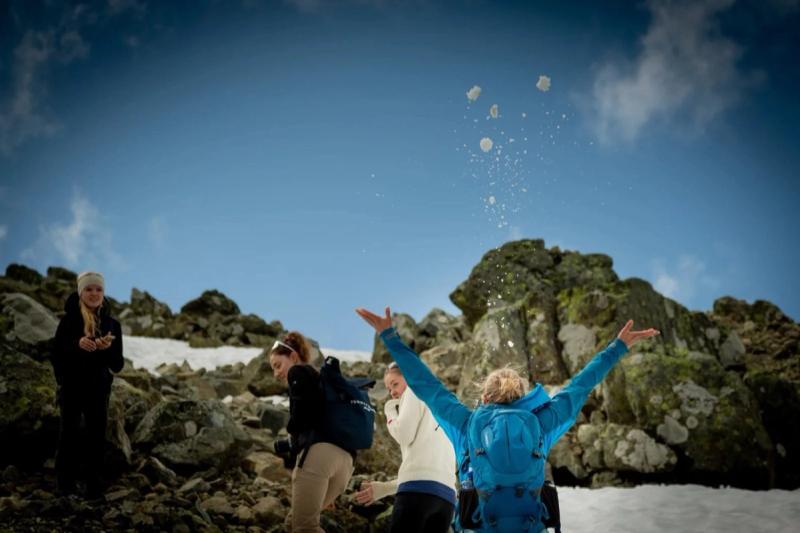 Hikers throwing snow in the air on a mountain top