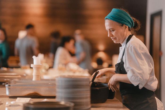 En kokk serverer middag ved buffeten, med gjestene i spisesalen bak