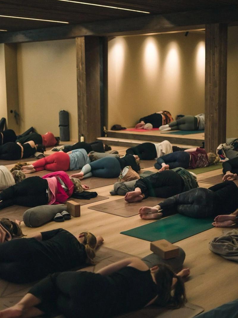 Students lying in relaxation in a large shala
