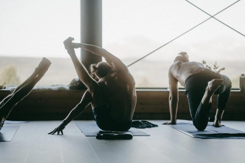 Three people practising on their mats in the shala