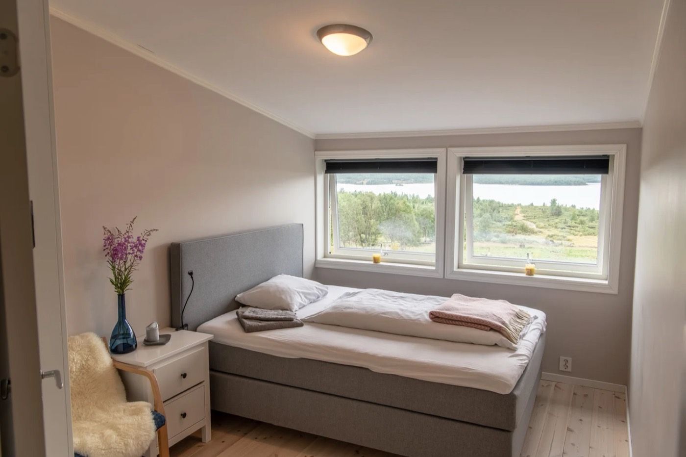 Et lyst hotellrom med dobbeltseng og vinduer mot fjellene