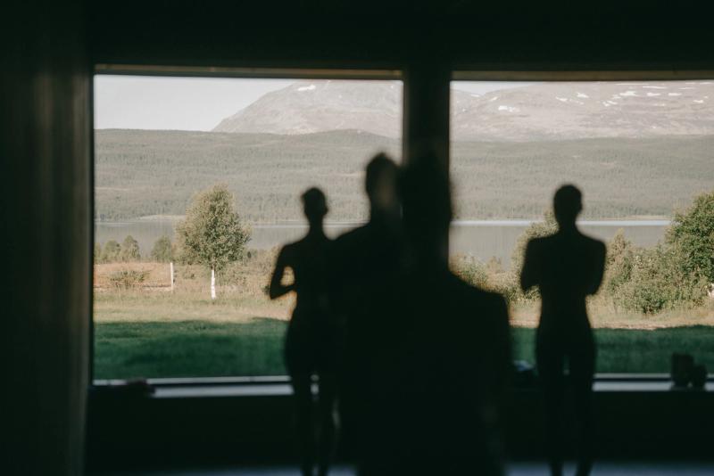 Three figures silhouetted against the shala window, the lake beyond