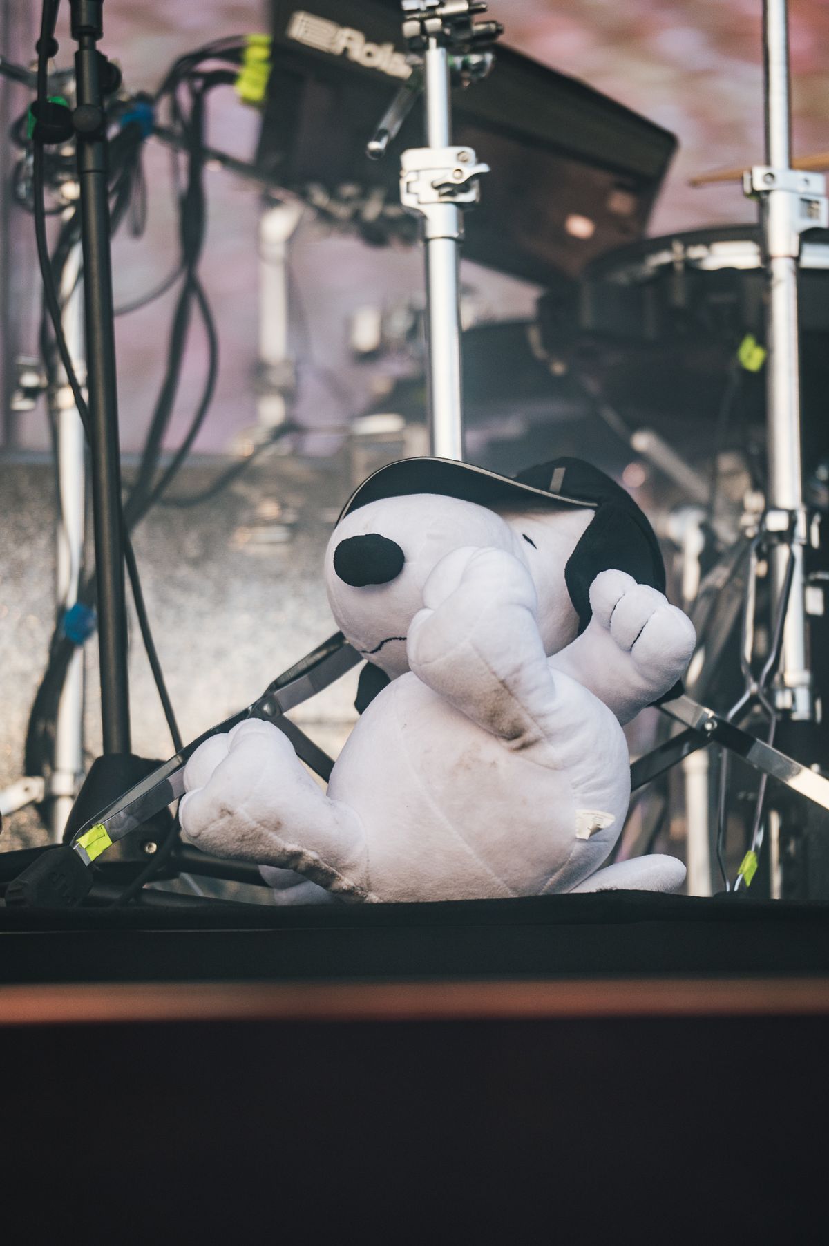 Un peluche de Snoopy con gorra sobre el equipo de batería en el escenario