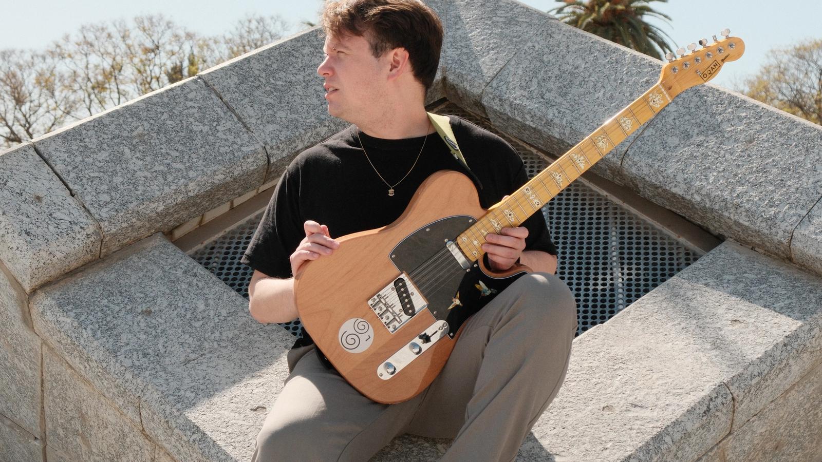 Luis Guevara sentado al aire libre con su guitarra Telecaster