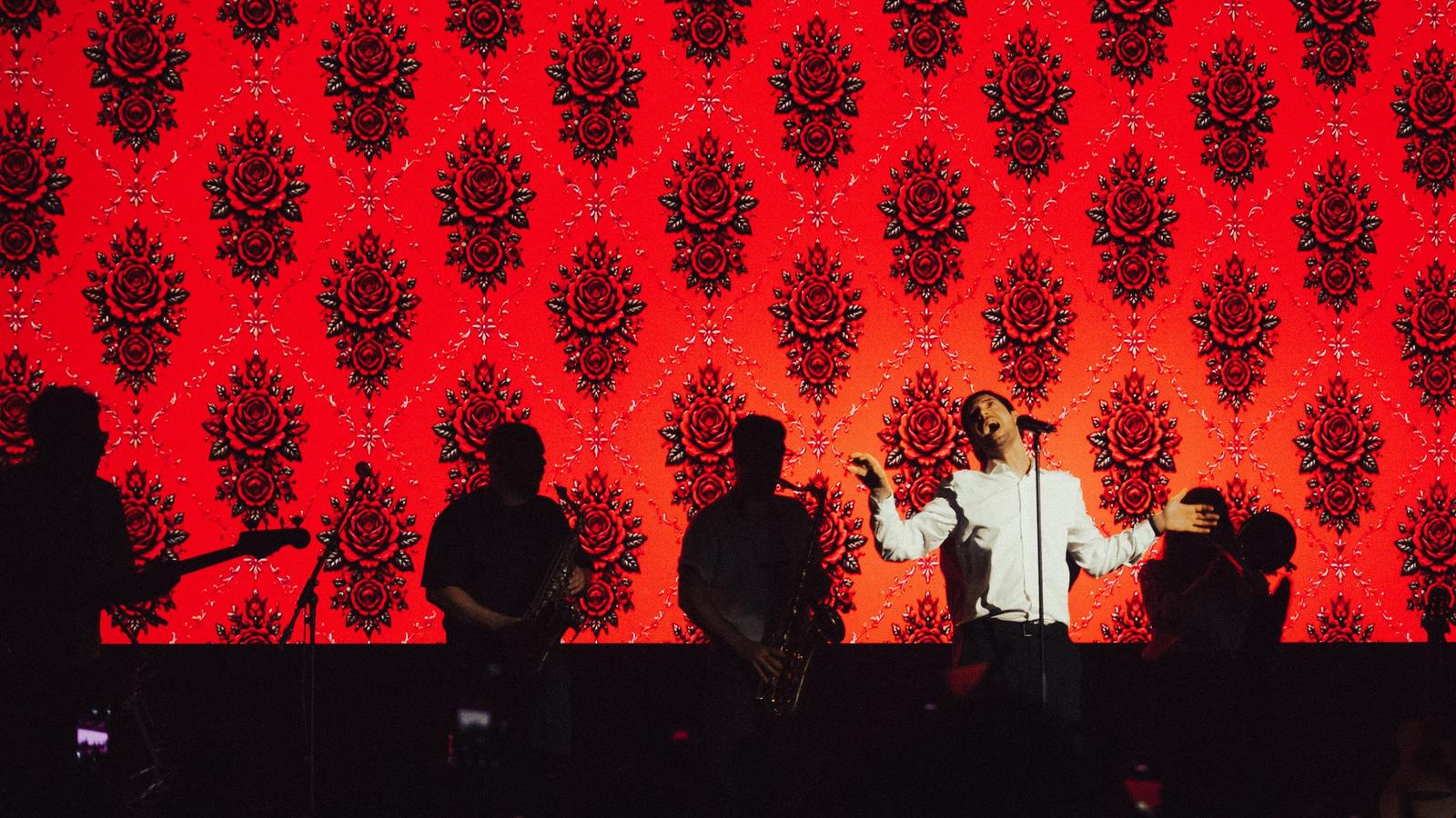 Cantante de El Kuelgue en el escenario con un fondo rojo