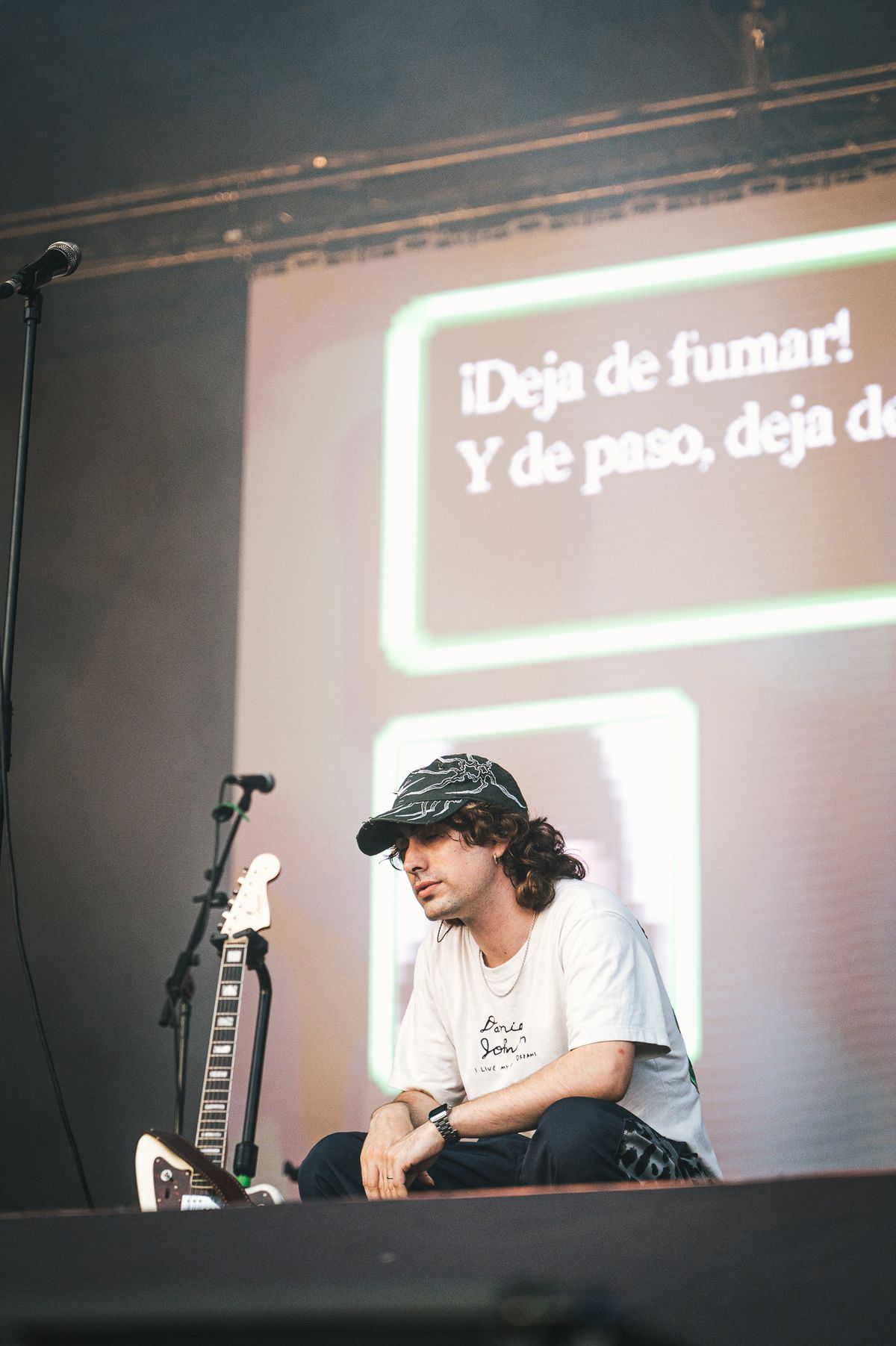 Marcos Crespo sentado en el escenario con visuales de texto proyectados detrás