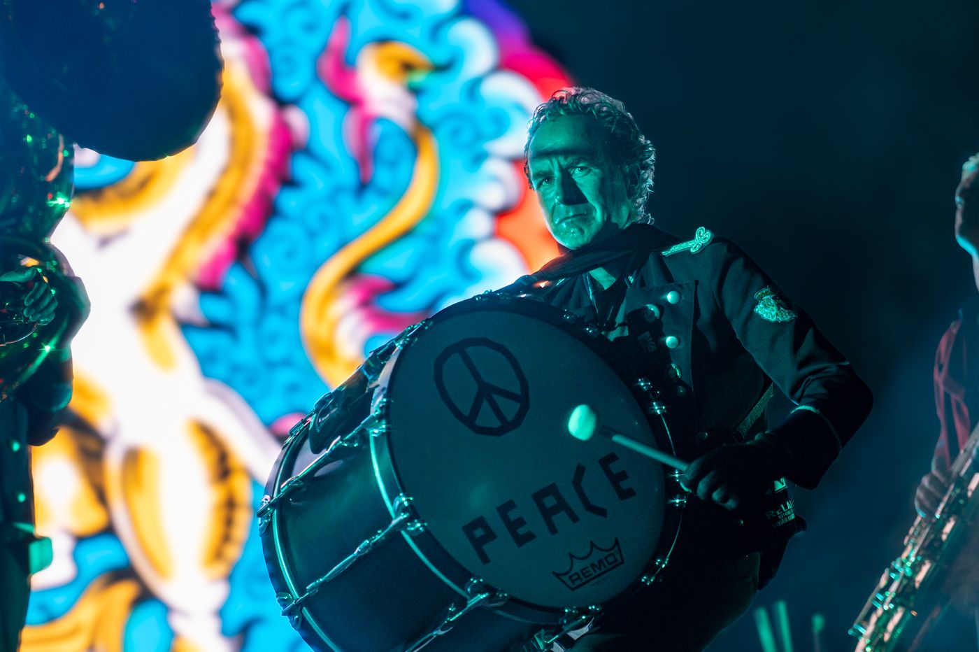 Baterista de Meute tocando el bombo con el símbolo de la paz, iluminado en verde