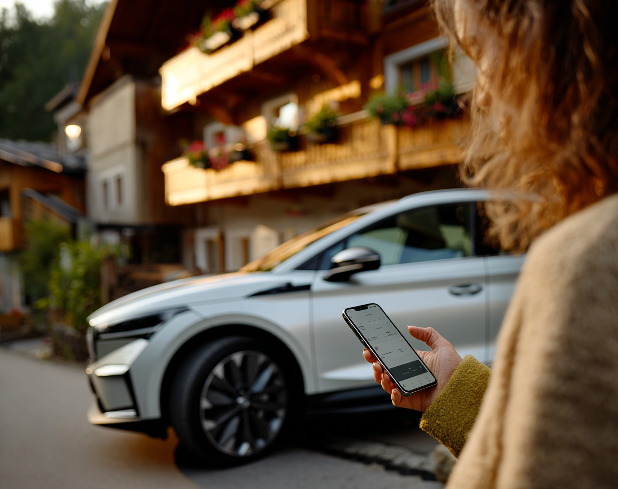 Frau mit Lade-App vor einem E-Auto