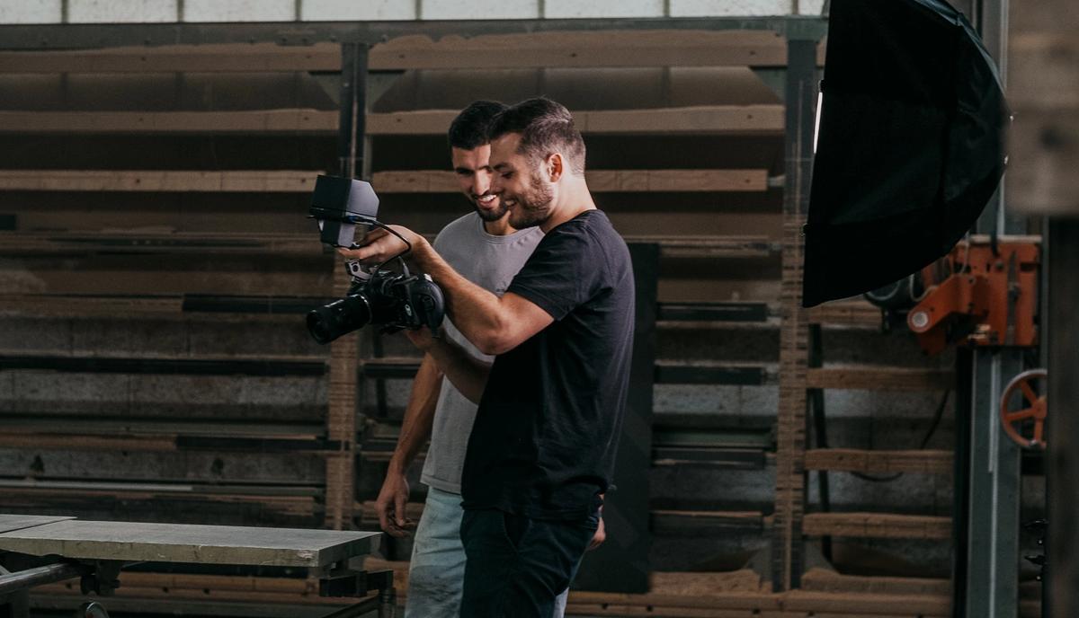 Zwei Personen mit Kamera und Softbox in einer großen Halle mit Holzdachstuhl.