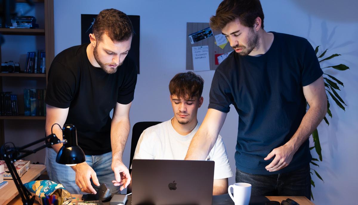 Mehrere Crewmitglieder stehen um einen Laptop auf dem Tisch und sichten das gedrehte Material.