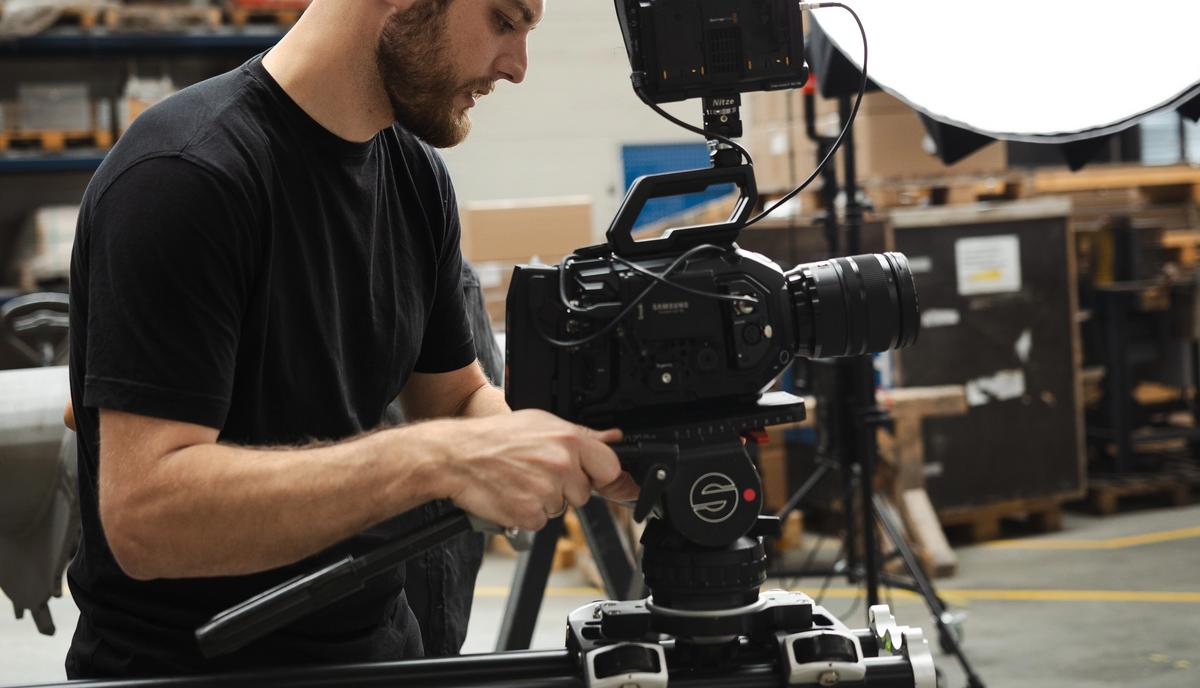 Kameramann bei der Einrichtung einer professionellen Filmkamera auf einem Slider in einer Industriehalle.