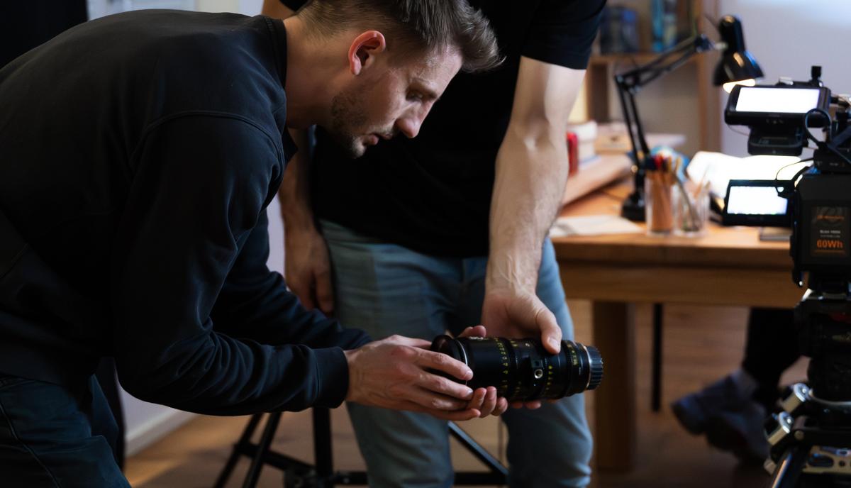 Zwei Männer beugen sich über die Kamera auf dem Stativ, links eine große Softbox.