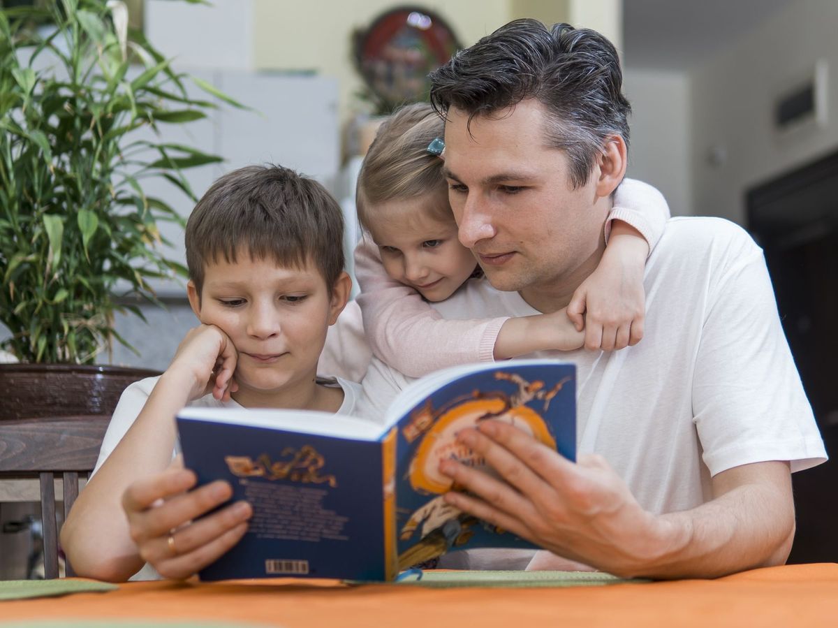 Father reading a book with his two children