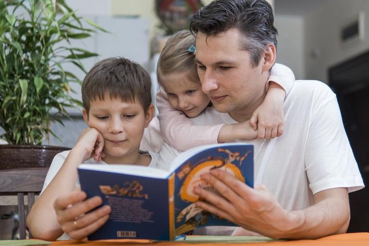 Father reading a book with his two children