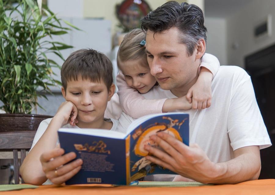 Father reading a book with his two children