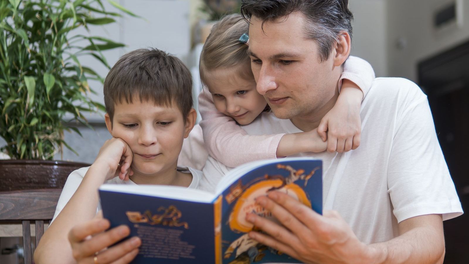 Father reading a book with his two children