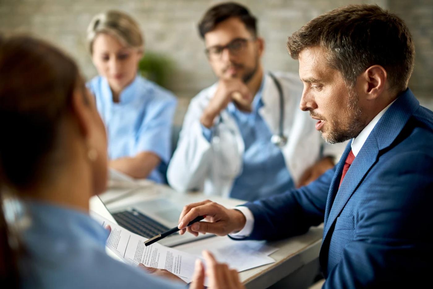 businessman and healthcare professionals reviewing documents as clinical advisors in a meeting