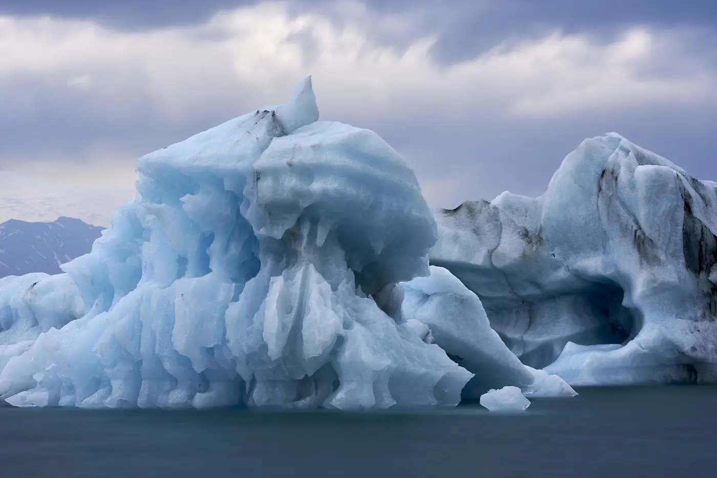 Blaues Eis treibt auf dunklem Wasser