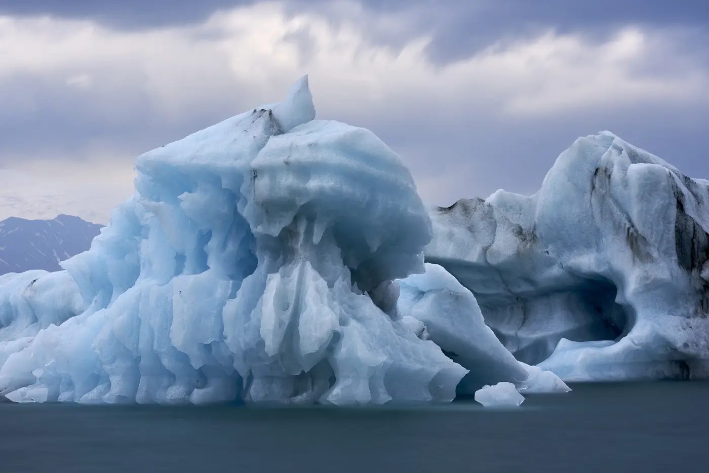 Blaues Eis treibt auf dunklem Wasser