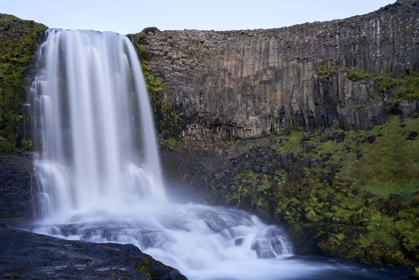 Ein hoher Wasserfall vor einer grünen Wand