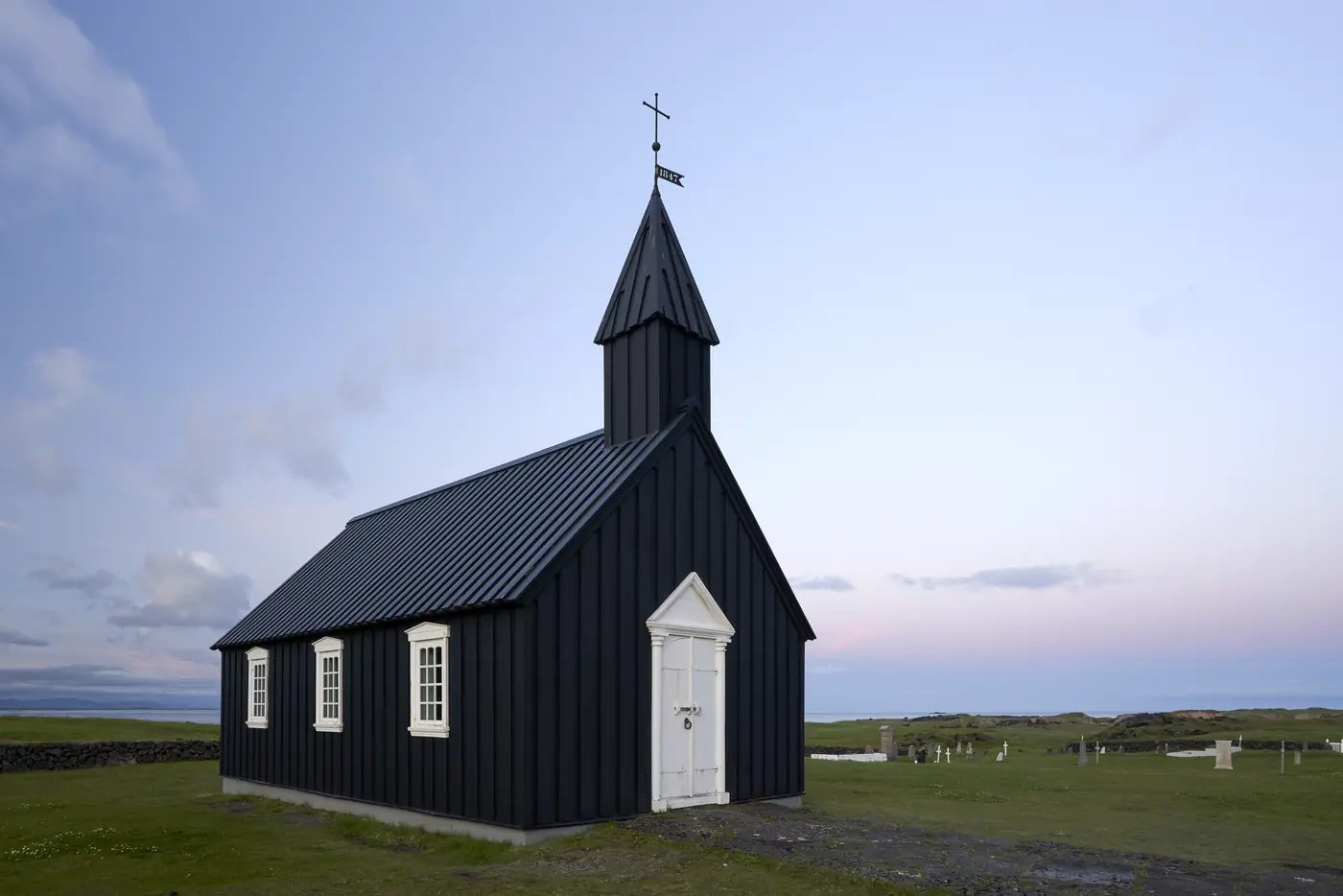 Eine schwarze Holzkirche unter dramatischem Himmel