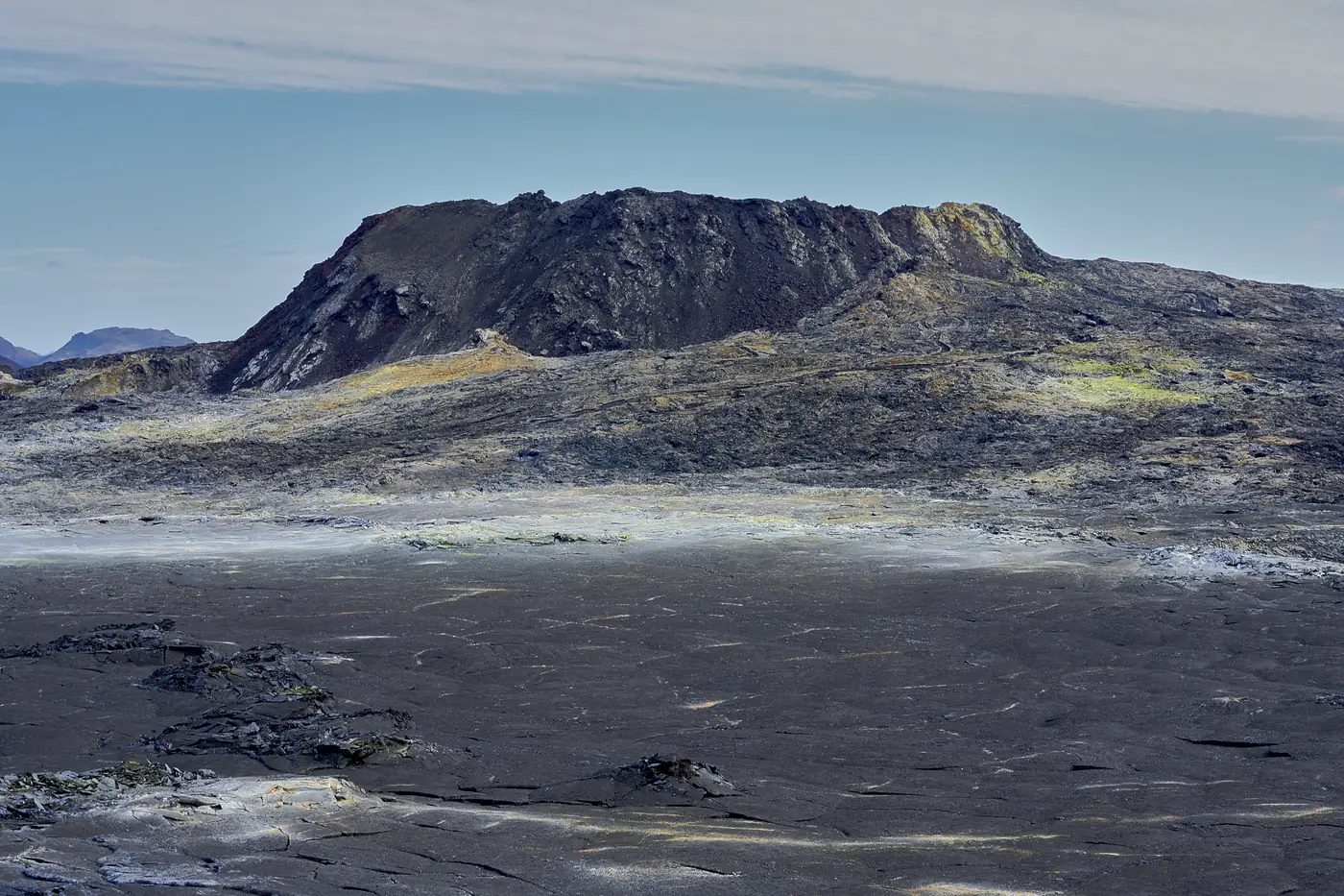 Ein dunkler Vulkanberg über einem Lavafeld
