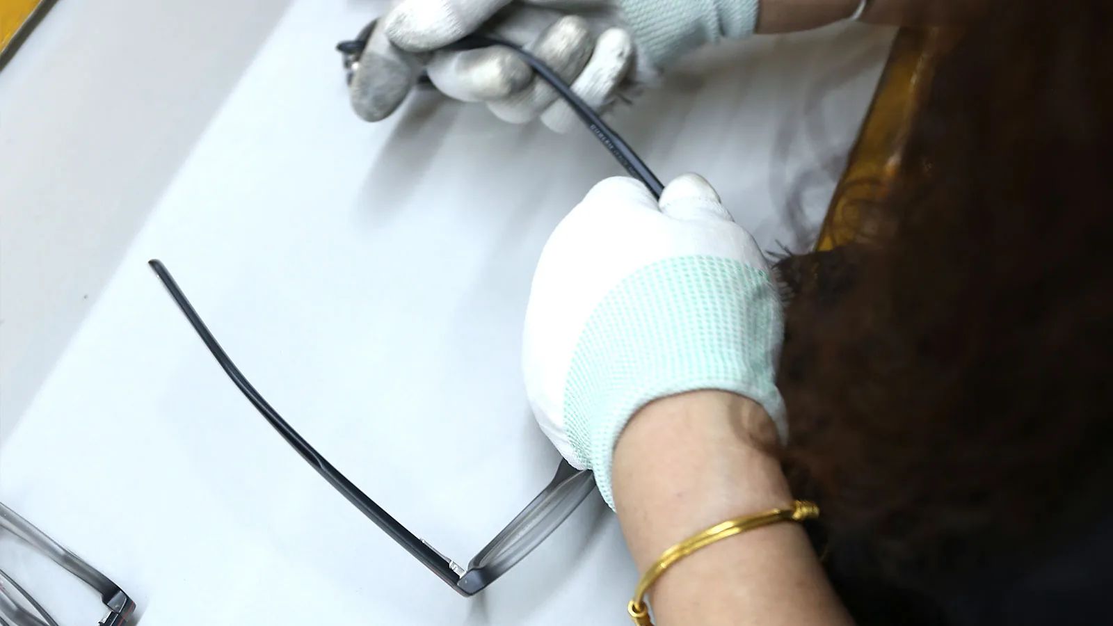 Worker inspecting sunglasses components during the assembly process