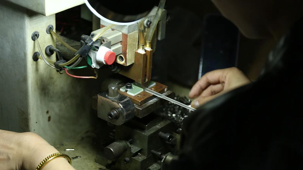 DOMI worker operating eyewear production equipment during sunglasses manufacturing