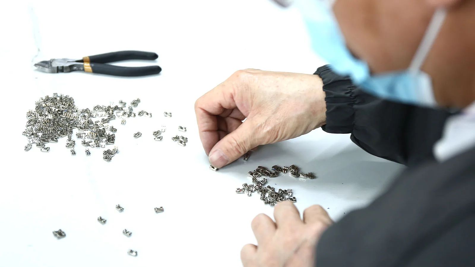 Metal spring hinge components being sorted before sunglasses assembly