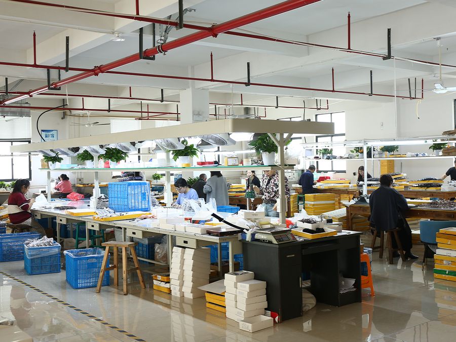 Workers assembling and inspecting sunglasses at the DOMI factory