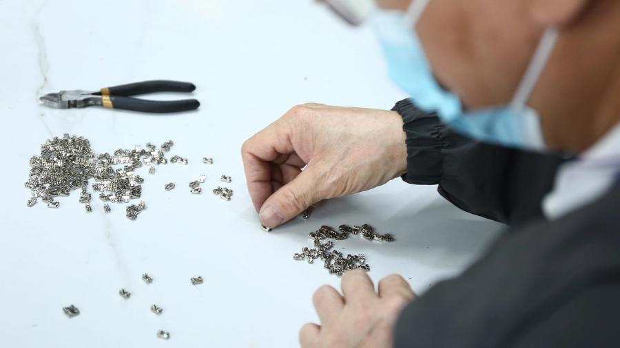 A worker handling small components during custom sunglasses production