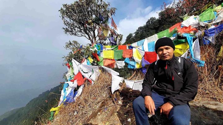 Govinda Shahi in a mountain setting with Nepalese prayer flags