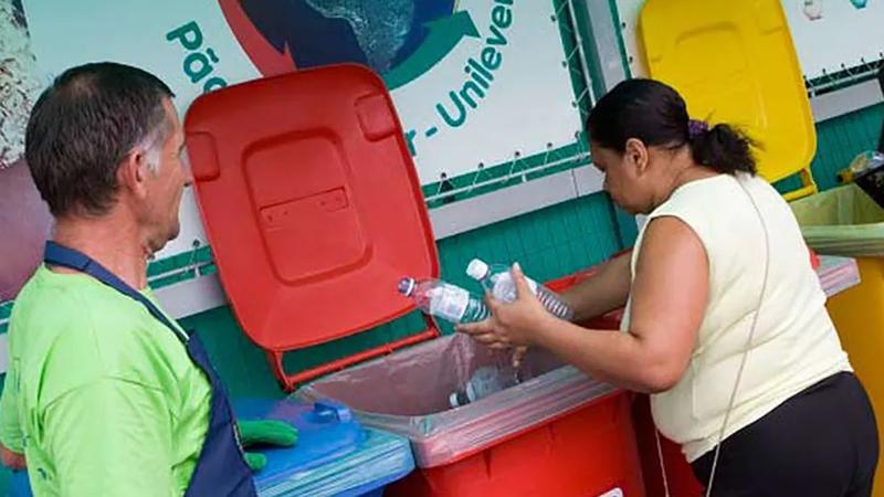 A woman placing plastic bottles in a recycling bin
