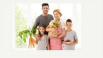 Family of mother and father with two children holding bag of groceries with fruits & vegetables"