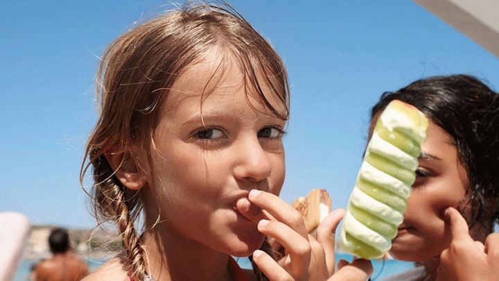 Young girl eats a Twister on the beach