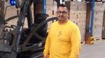 Image of Miltiatis standing in a warehouse next to his forklift truck