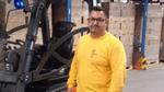 Image of Miltiatis standing in a warehouse next to his forklift truck