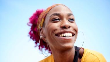 Young woman smiling against a blue sky
