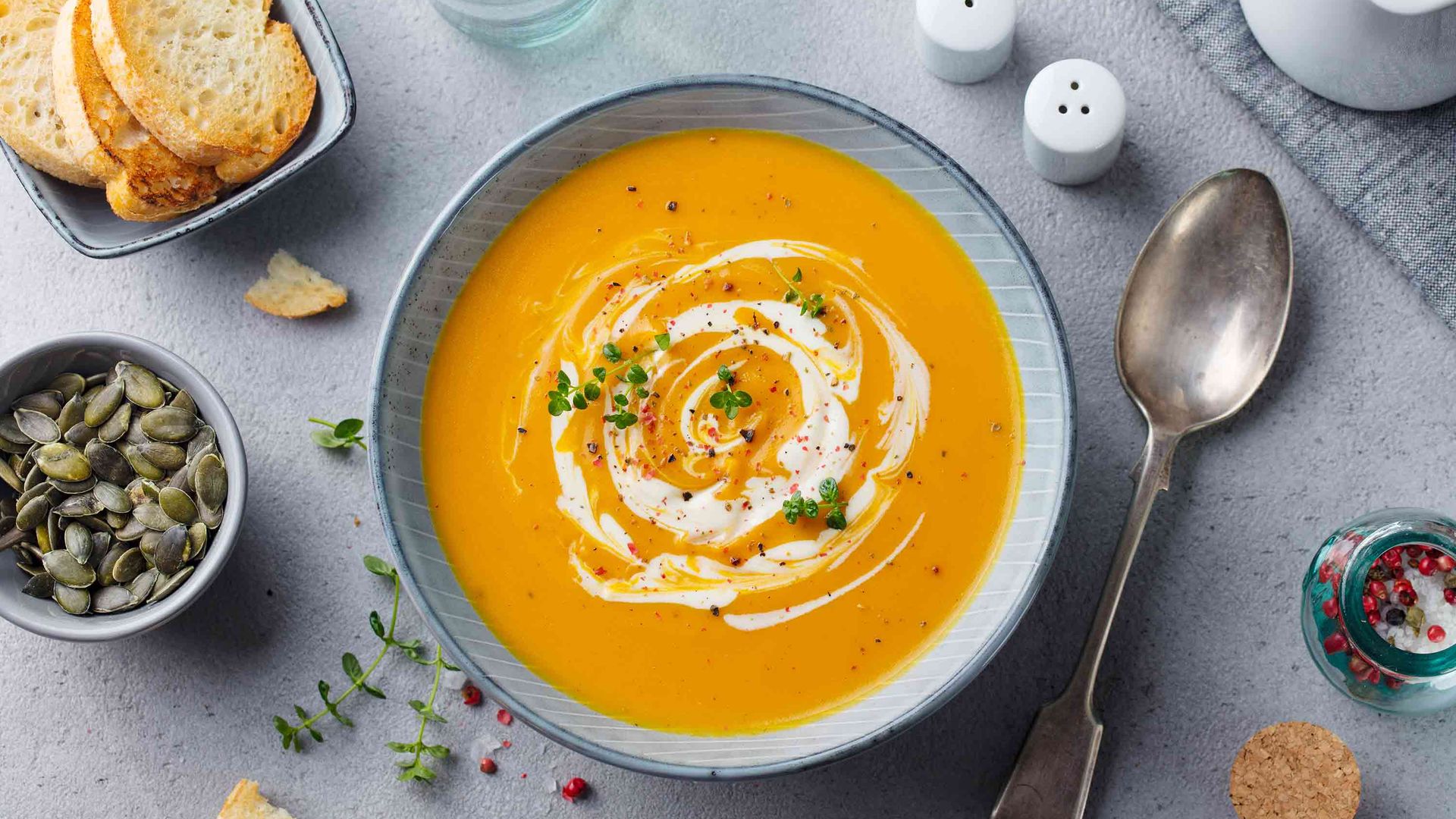 A bowl of pumpkin soup swirled with yoghurt, pepper and herbs