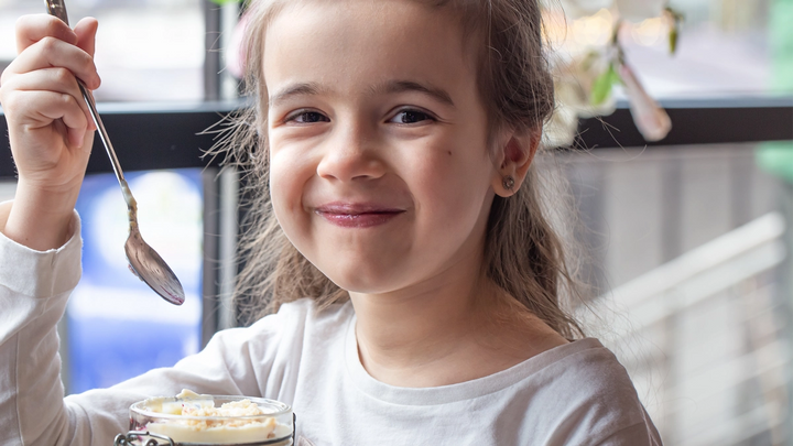 A young girl smiling and eating a dessert
