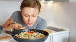 A woman savouring the aroma of a pan of rice and vegetables