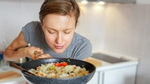 A woman savouring the aroma of a pan of rice and vegetables