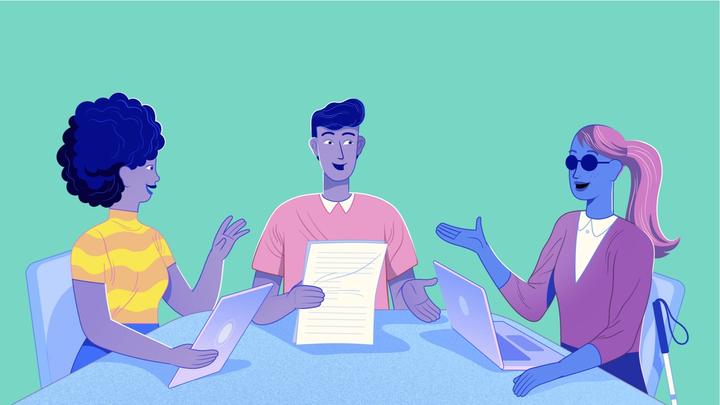 Drie werknemers aan een bureau die samenwerken, waarvan 1 persoon blind is