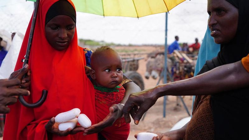 Woman with baby in Africa being handed bars of soap by volunteer
